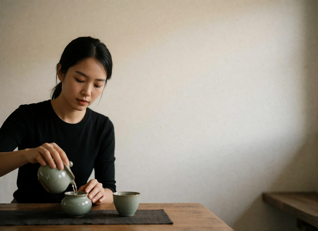 Vietnamese woman pouring tea at a low wooden table in a quiet tea house.